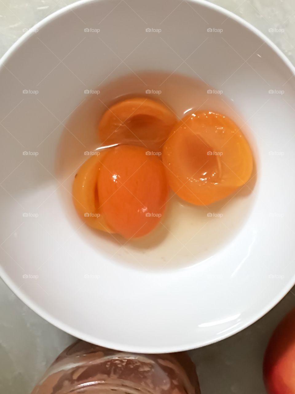 Bright orange apricots in white bowl closeup