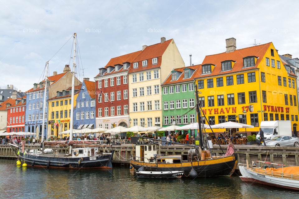 Nyhavn area in Copenhagen, Denmark. Colorful houses and sailboats. Nordic design. Touristic and famous spot. Water and cloudy sky. Restaurants next to the water