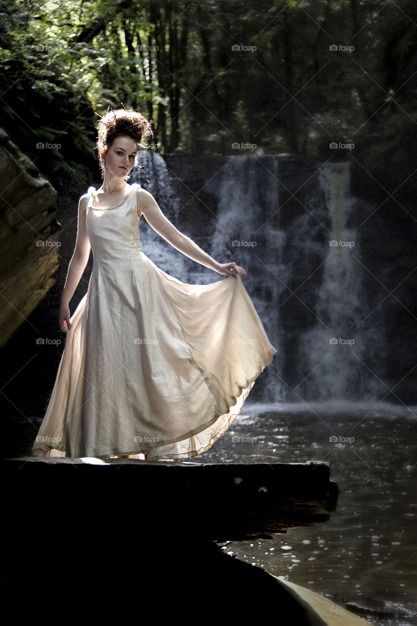 Young woman posing near waterfall