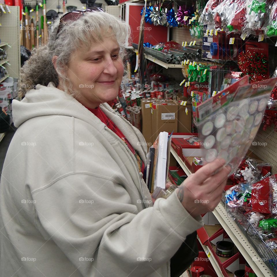A woman views a package of stickers to use to decorate Christmas gift packages while shopping during the holiday season. 