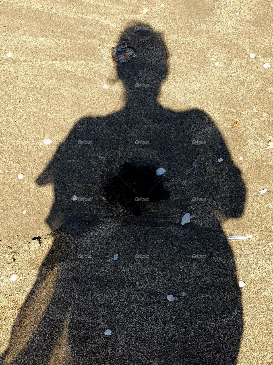 Shadow of a mother to be on beach sand