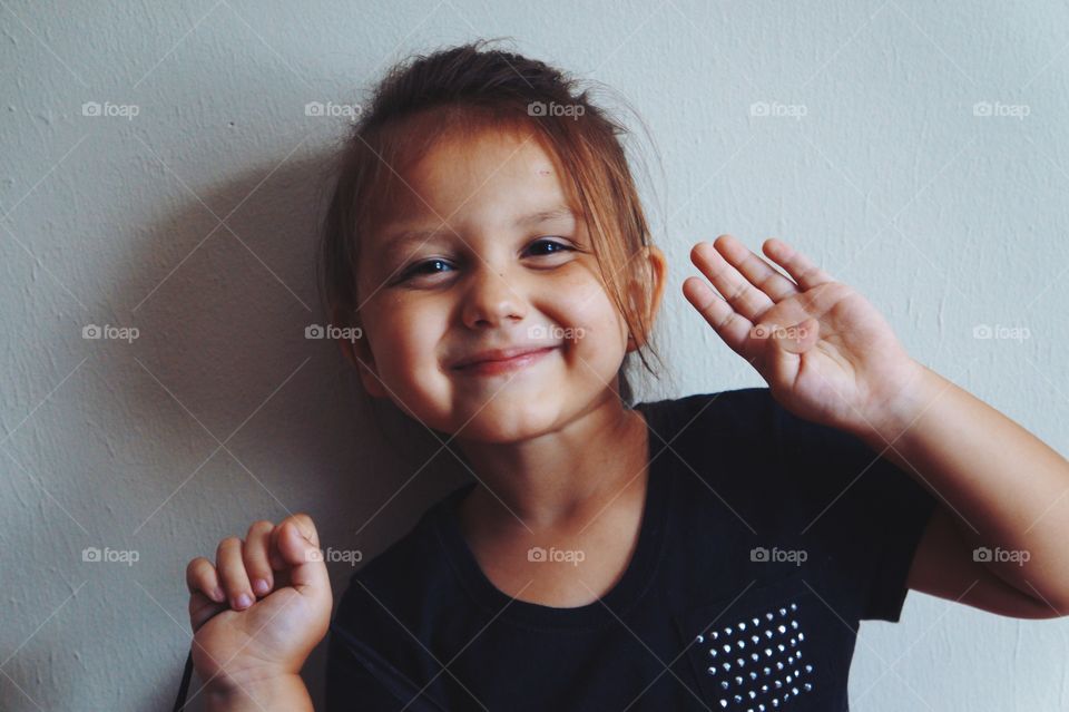 Little cute girl standing against wall