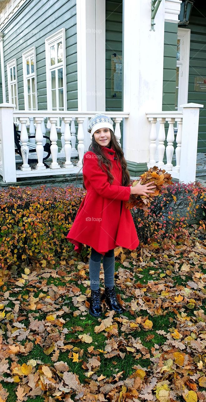 Little girl with vintage clothes holding autumn leaves in her hands