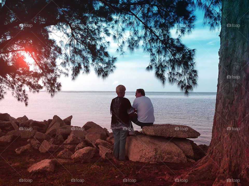 A loving couple enjoying sundown on a late summer day at the oceans shore.