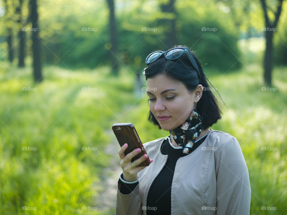 Beautiful brunette woman using smartphone in the park 