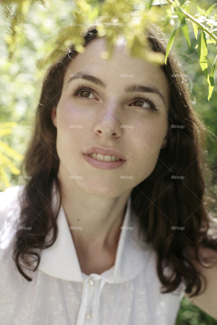 girl in white in spring nature. young, woman in white shirt by the green branches