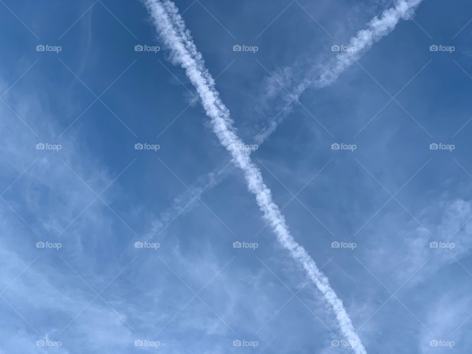 The lines of white contrails crossing a bright blue sky.