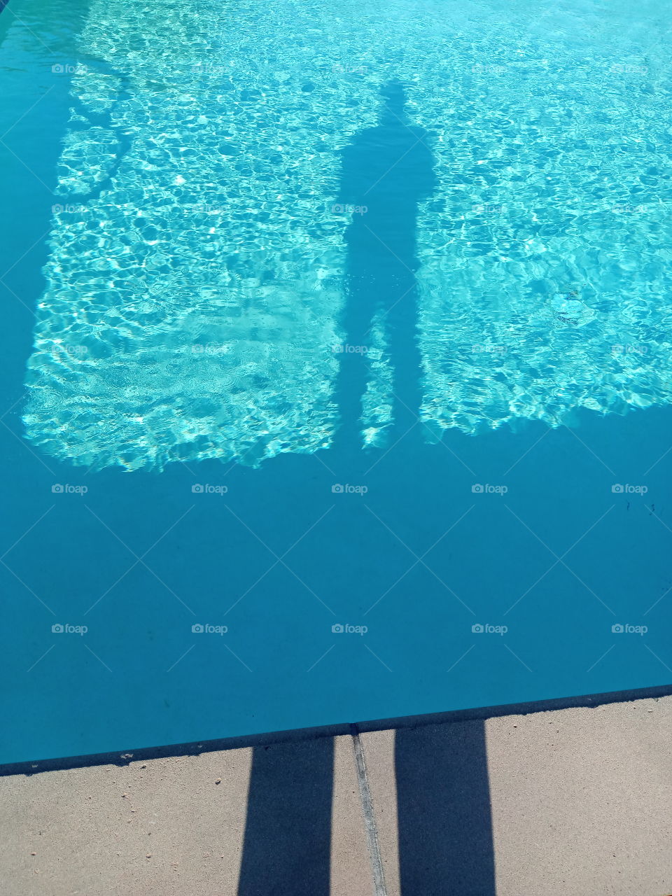 pool shadow of a person standing at the edge of a crystal blue Waters