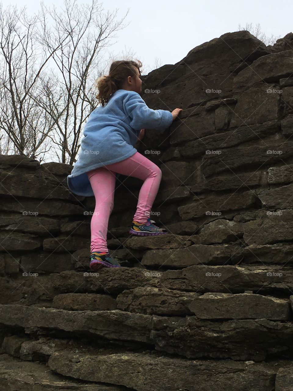 Girl climbing stone wall built at turn of the century
