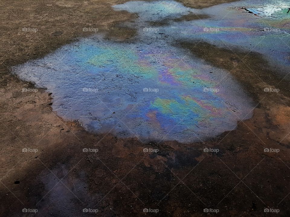 Puddle of colorful gasoline spoil on the concrete floor  oil spill