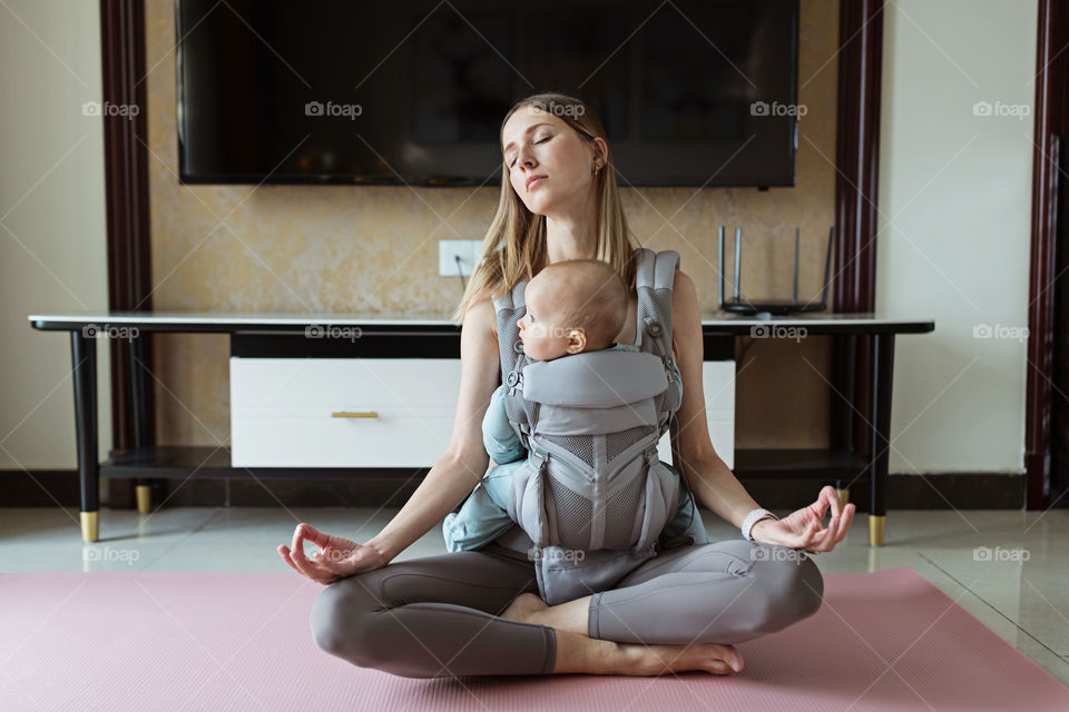 Young Caucasian mother practicing yoga at home with baby