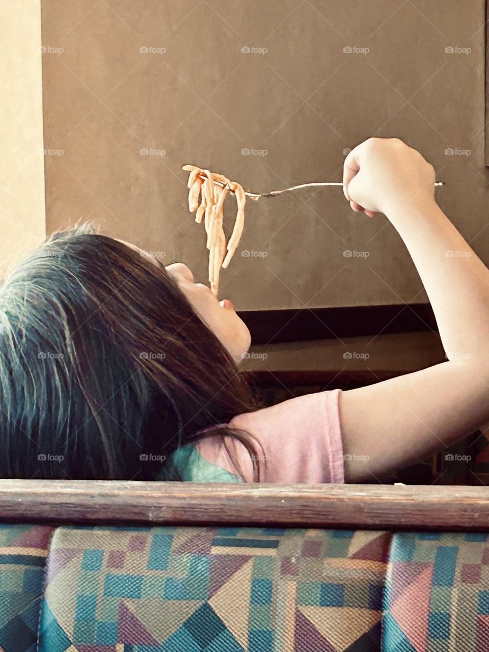 Little girl in a restaurant eating spaghetti 