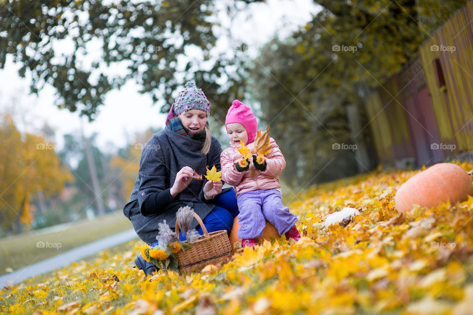 Mom and baby girl playing in autumn park