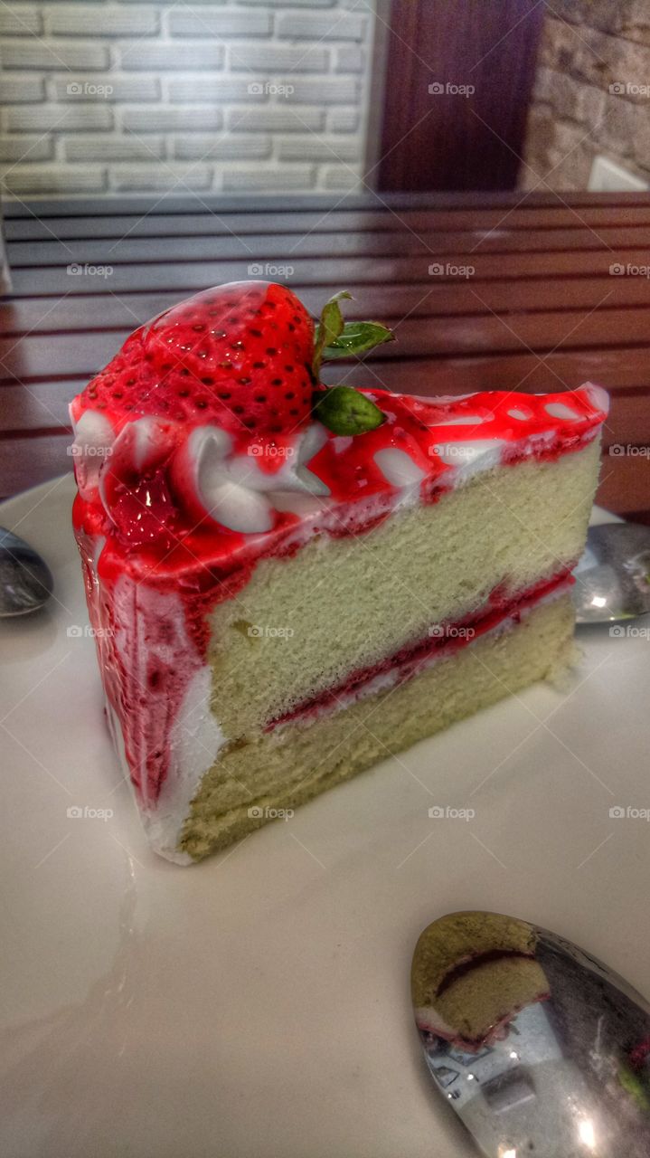 Slice cake with red strawberry on plate
