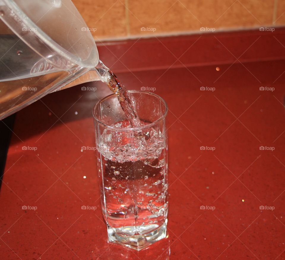 It is a jug pouring water into a glass. As a healthy way of life you have to drink water. Bubbles can also be seen in the glass of water.