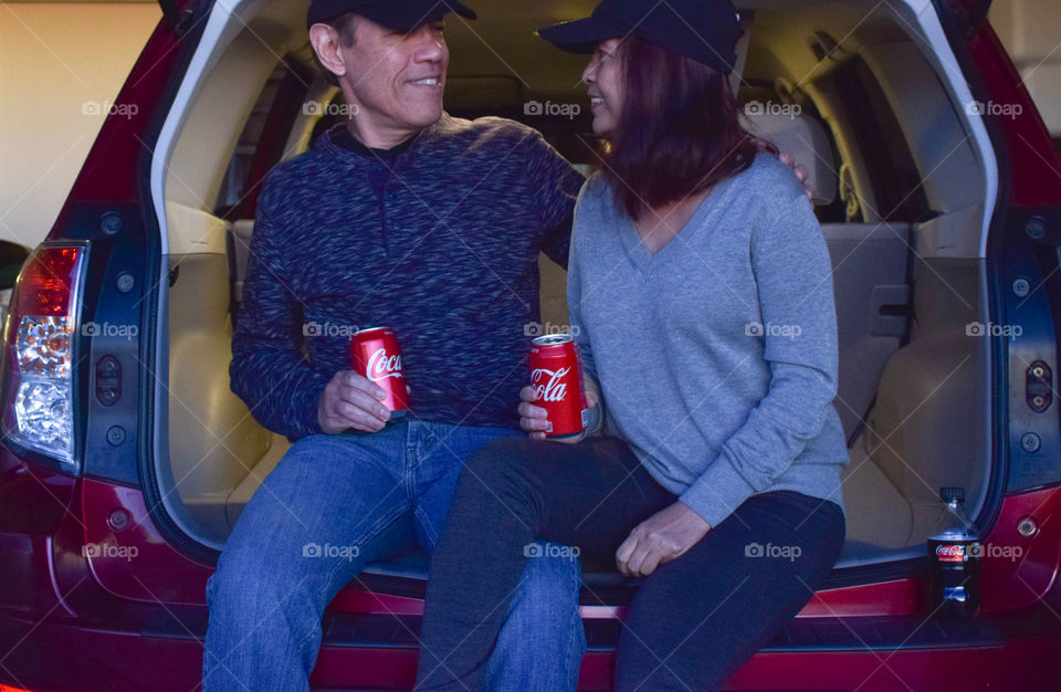 A couple having a good time drinking Coke in SUV hatchback 