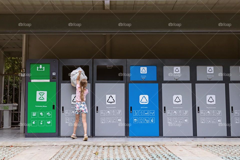 Kid throws sorted garbage into a container for recycling