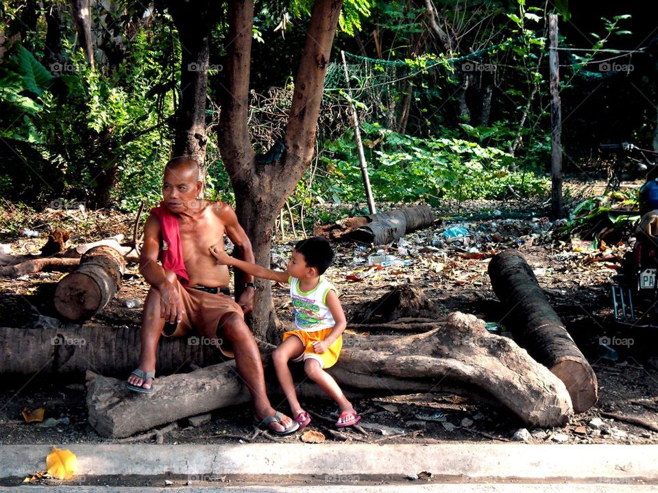 asian grandfather and grandson rest under the shade of a tree