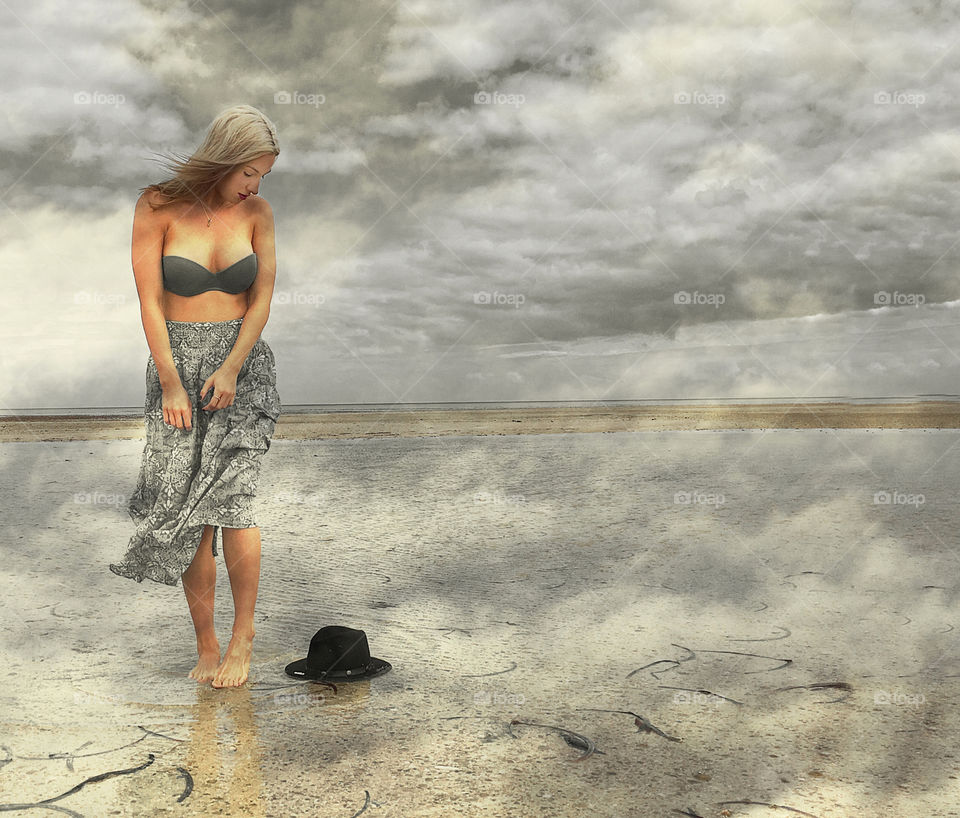 Fantasy Dream state, beautiful blonde woman in bikini top and skirt on stormy beach