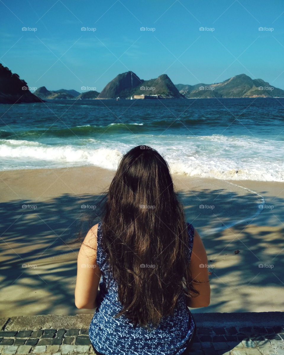 mulher de cabelo longo olhando para o mar