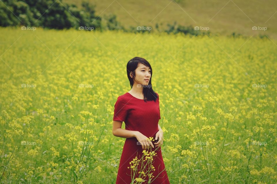 Asian woman standing in Oilseed rape field
