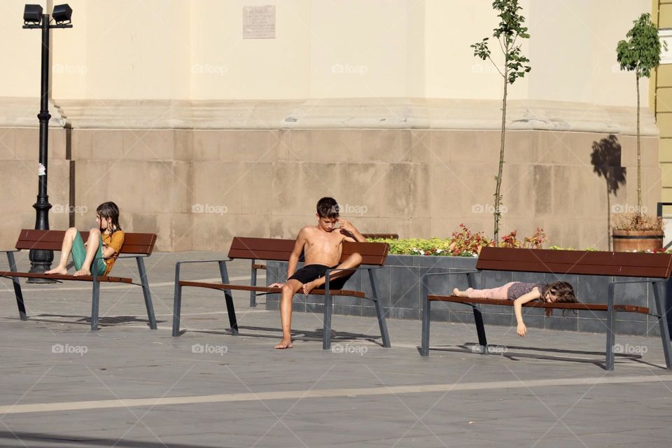 Kids drying at the sun on city square benches 