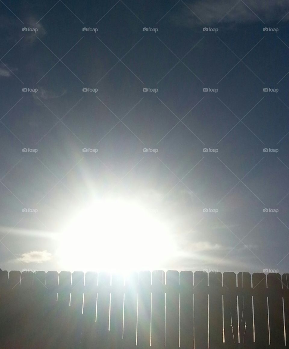 Sunrays shining above a fence in November