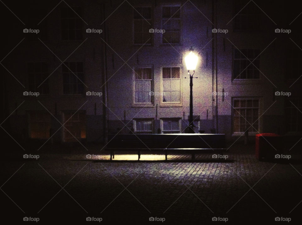 A bench in Amsterdam, lit by a single street light.