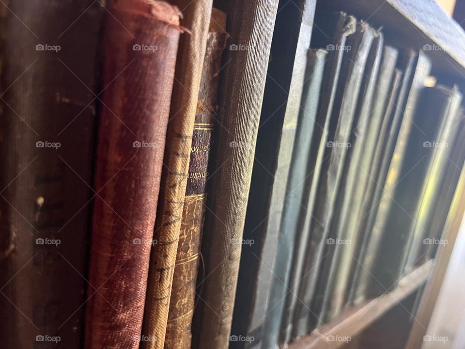 Old, worn books in a wooden bookcase. Found in an old historic home, Colorado, USA. 