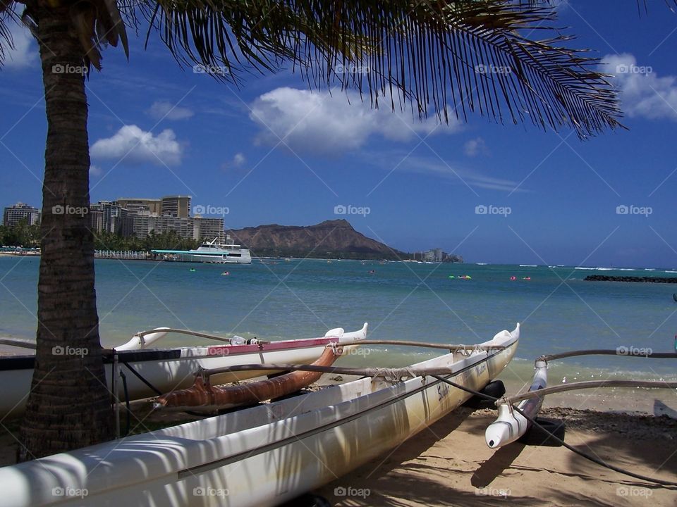 Outrigger Canoe & Diamond Head. An outrigger canoe on a beach in Waikiki with Diamond Head in the distance.