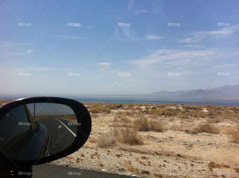 The road reflected in the car's side mirror while driving through California desert