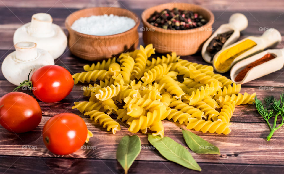 Raw pasta with ingredients and wooden accessories