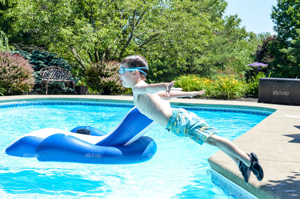 Young boy jumping into a pool