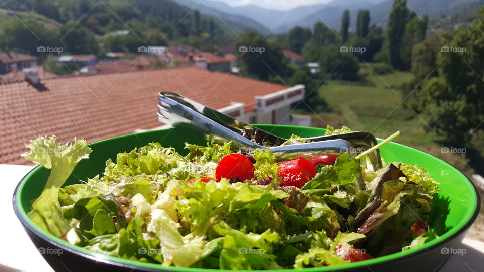 Green salad at the countryside. with lettuce, baby tomatoes, olive oil, seeds, arugula, cranberries, parmigiano. countryside