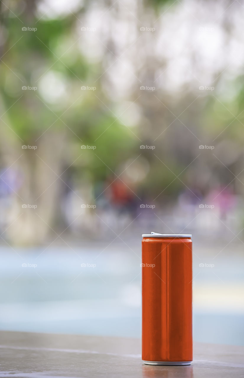 Canned drink red on the wooden chair Background blurry trees in garden