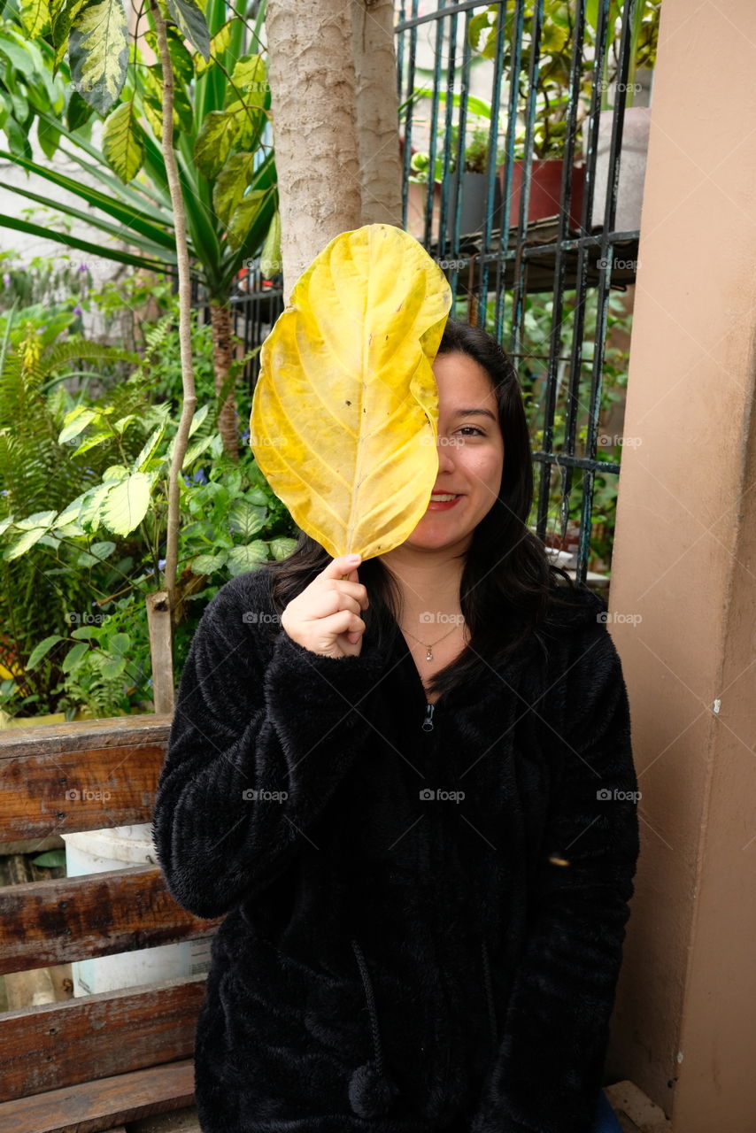 Happy woman with yellow leaf smiles with happiness as she leaves for vacation