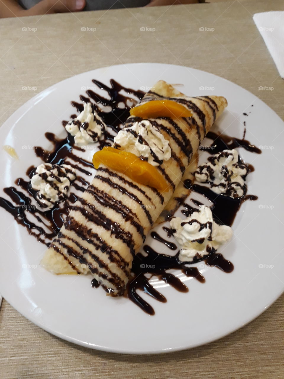 Mango-stuffed Crepes top with chocolate drizzle and whipped cream!