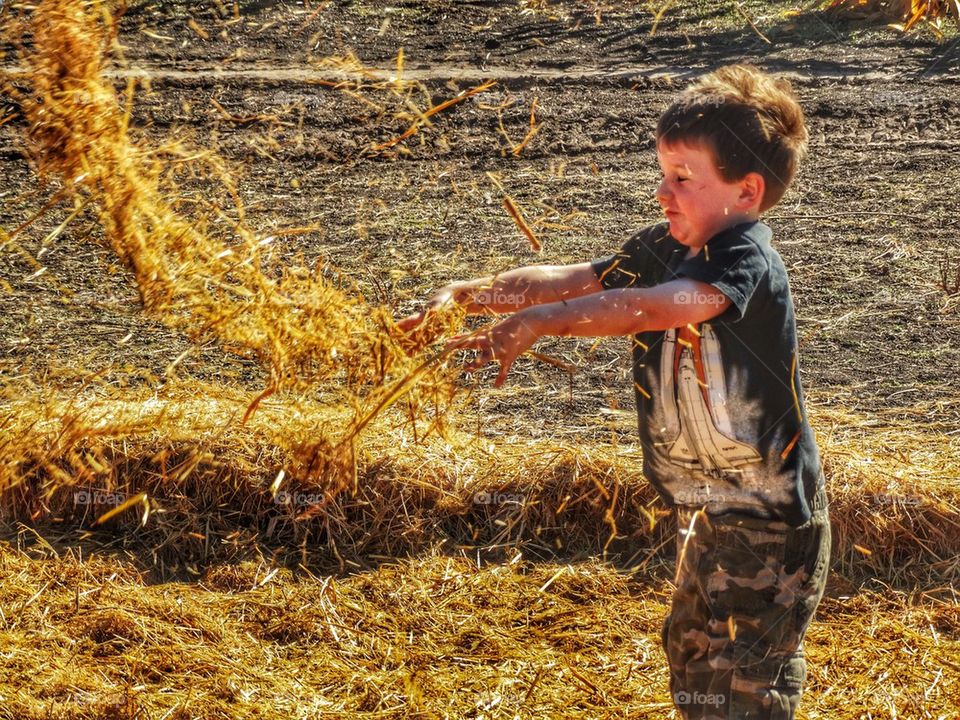 Boy Playing In A Haystack