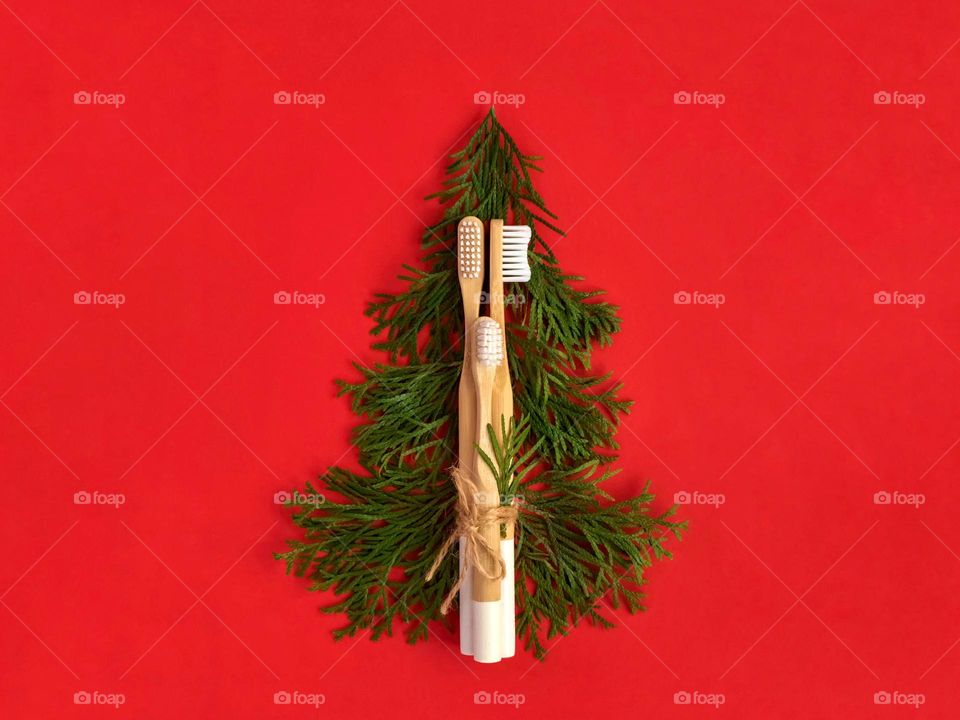 Bamboo toothbrushes tied with natural rope. White cedar branches in the shape of a Christmas tree.