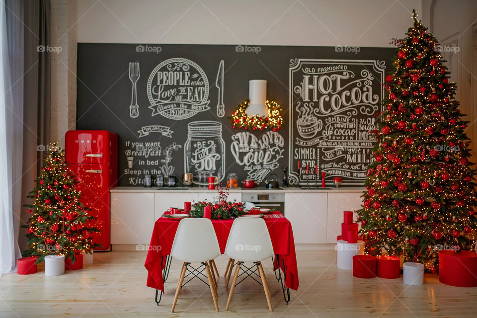 Festive winter cozy kitchen interior with garlands, decorations and gifts.  Christmas dinner at the decorated table.