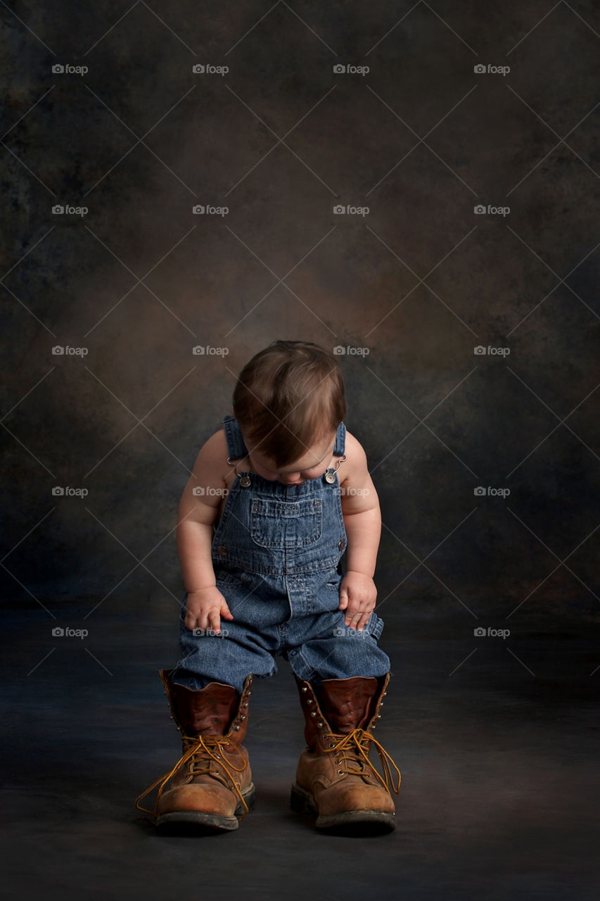 toddler boy wearing bibs overalls and dads boots
