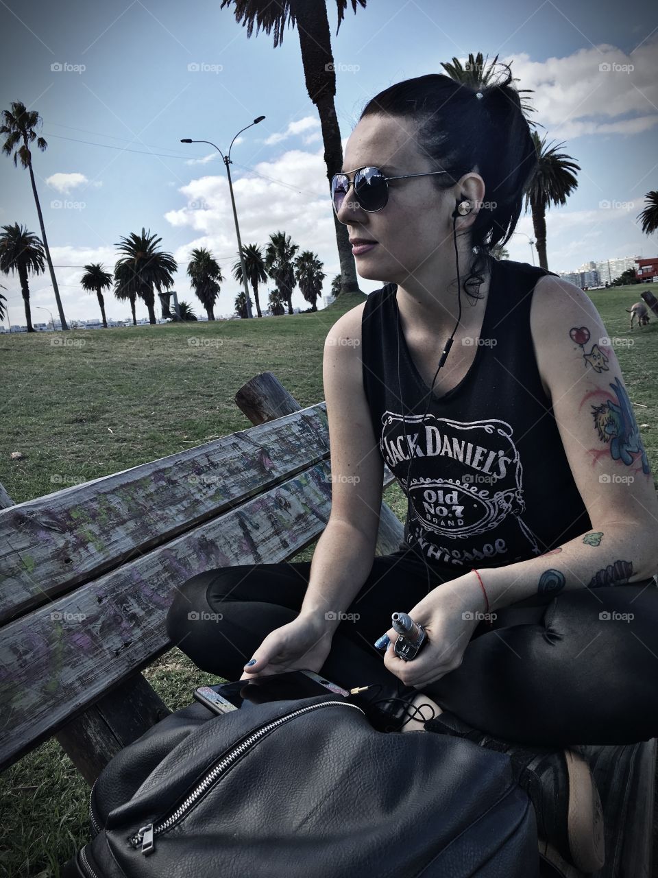 Woman with tattoo sitting on bench listening to music