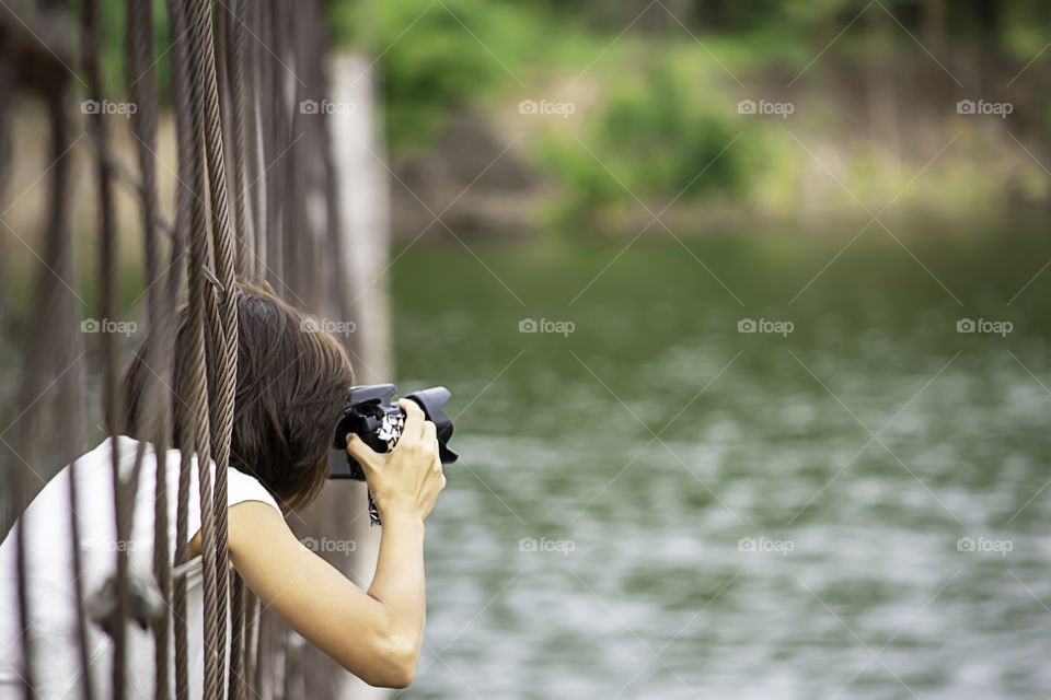 Hand woman holding the camera Taking pictures on  wooden bridge Background Kaeng Krachan dam phetchaburi , Thailand.