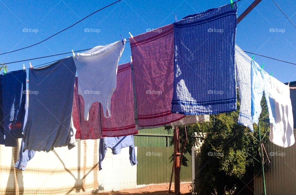 Clothing and dish towels laundry hanging on outside clothesline 