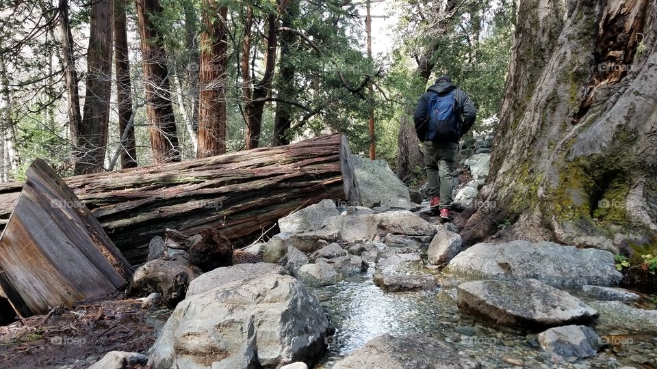 man hiking on a rocky trail with a puddle of water in the mountains