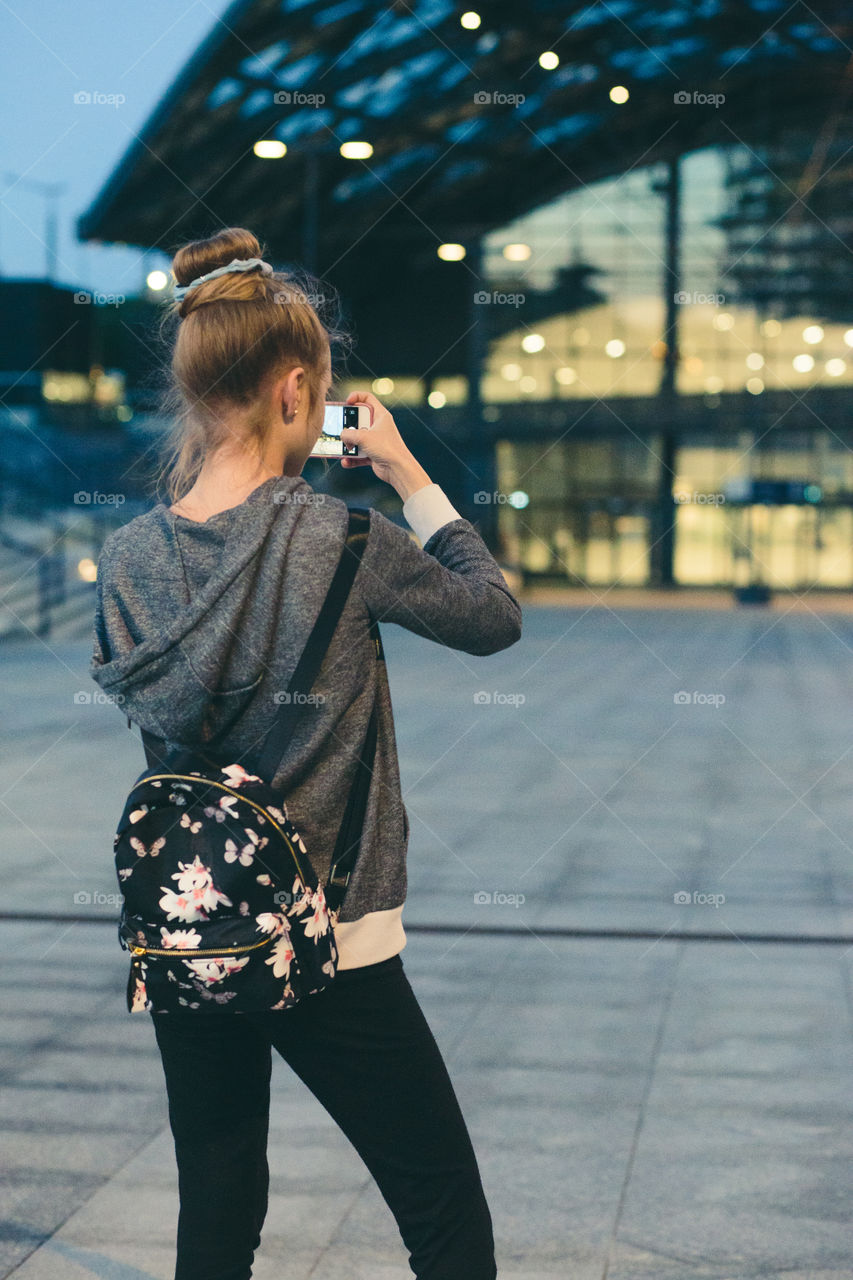 Young woman taking photos using a smartphone in the city at night