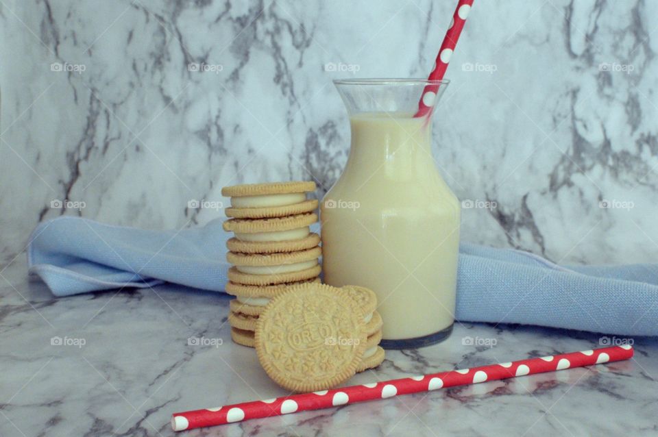 Oreo double stuff cookies stack next to a carafe of milk on a marble backdrop