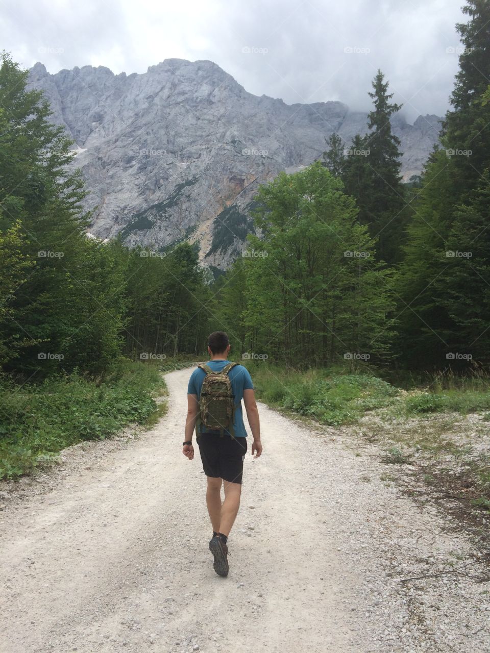 Rear view of a man walking on dirt road