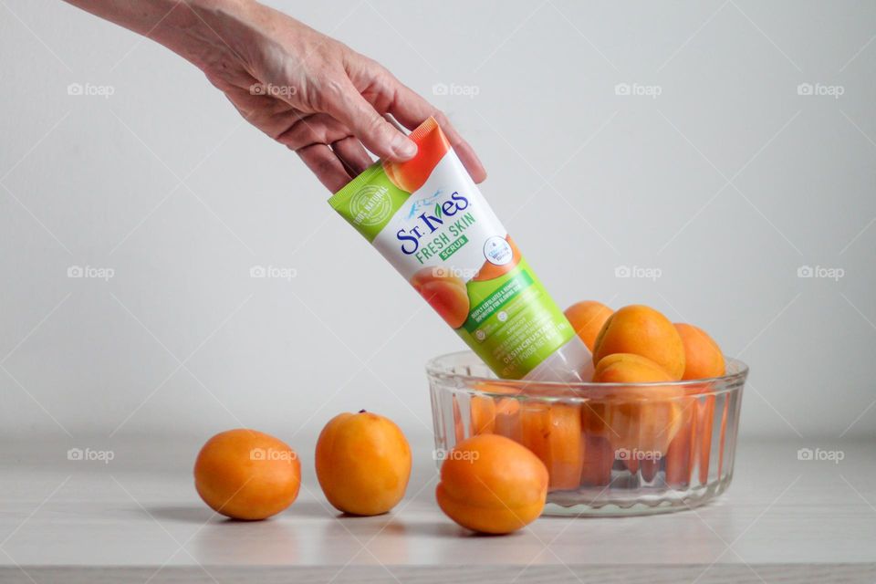 Hand is holding tub with scrub by St.Ives