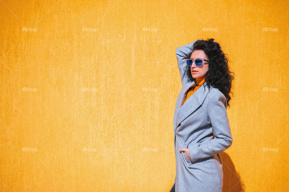 A woman in sunglasses near acid yellow wall